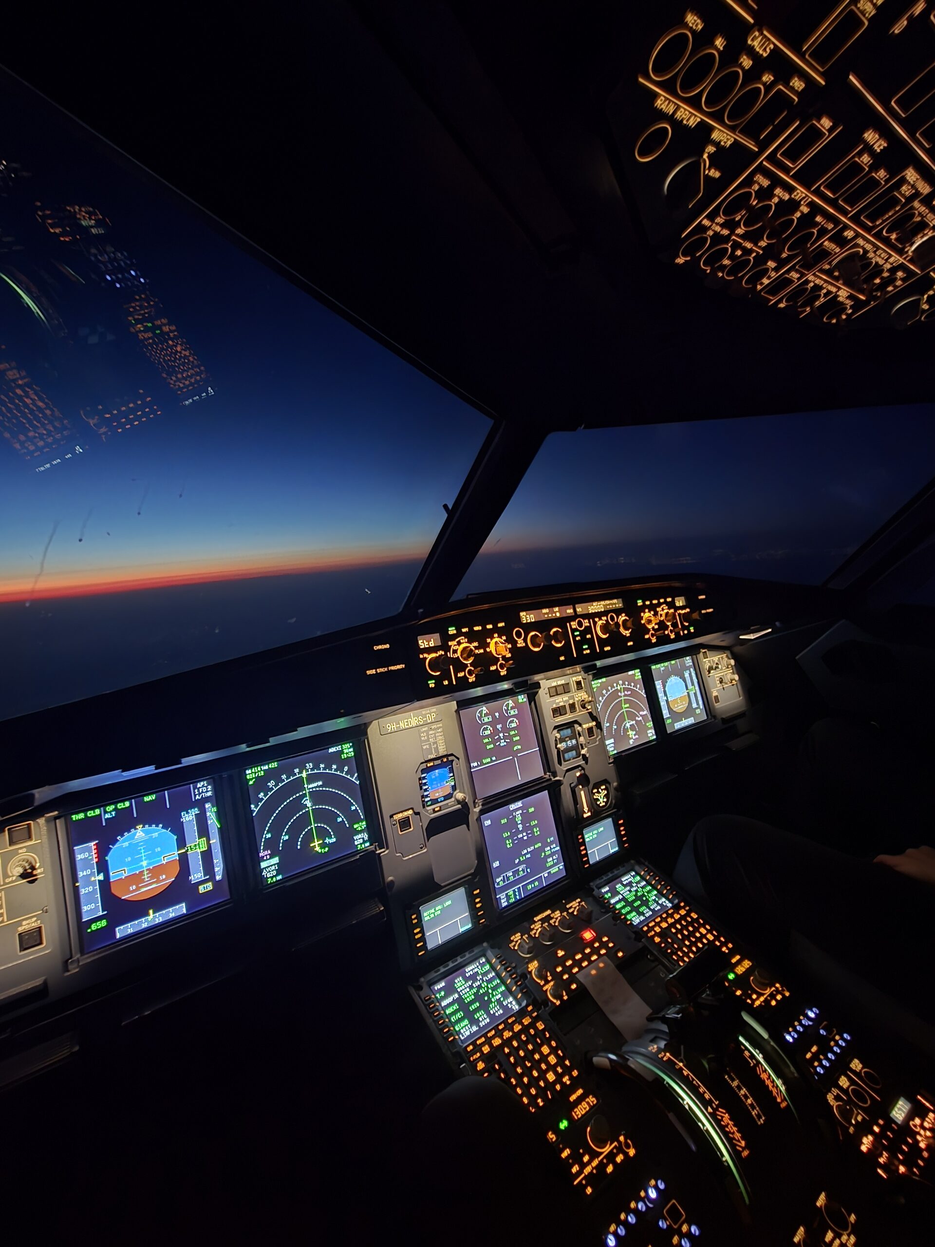 A320 full-flight simulator cockpit, instrument panel lit at dusk